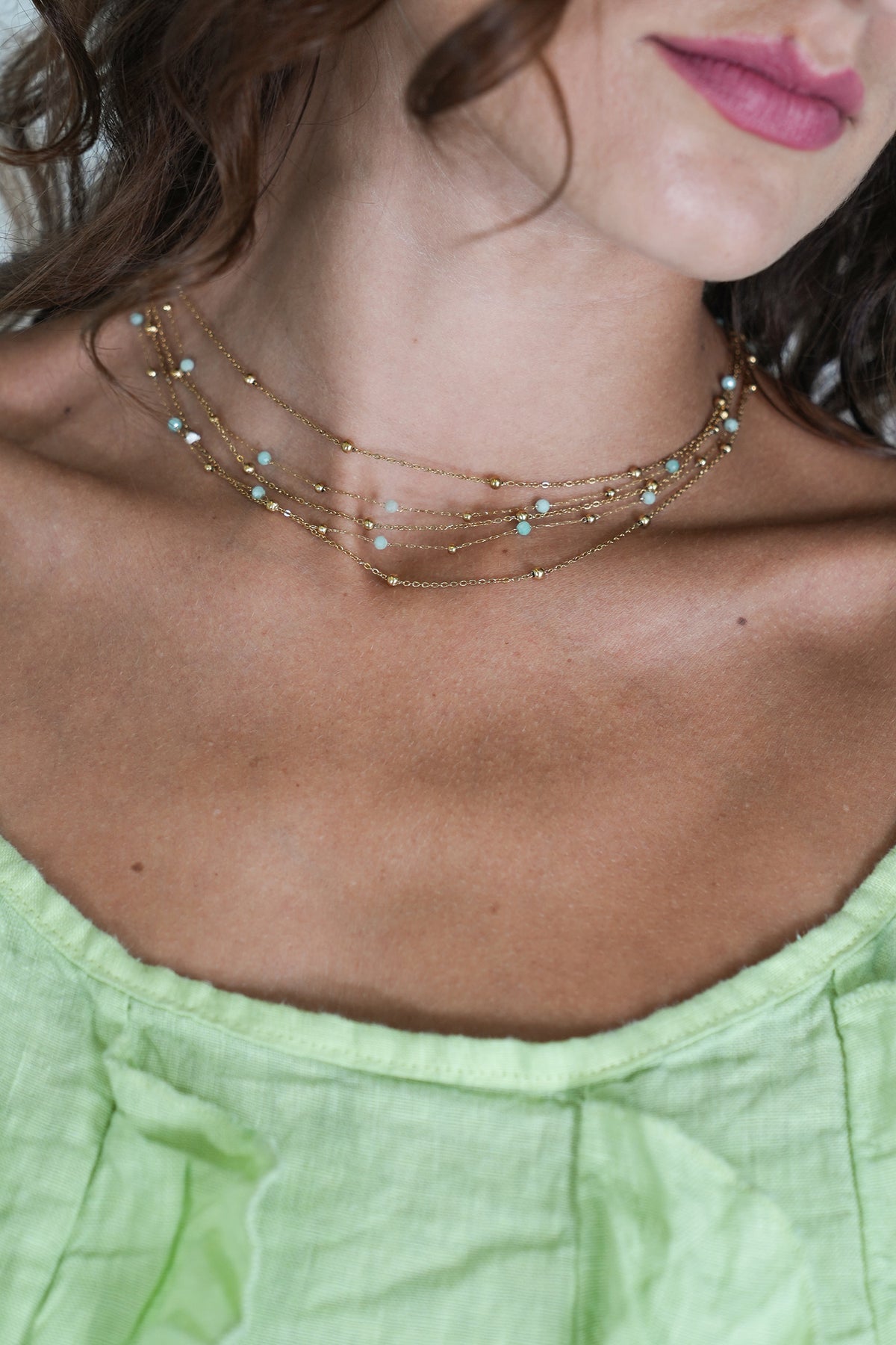 Necklace with small stones worn by a person with green top