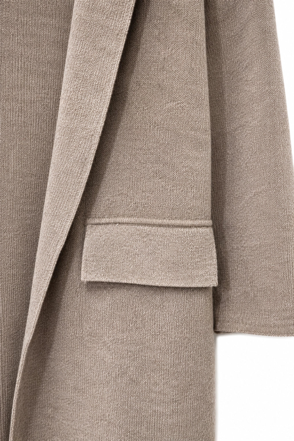 Close-up of a taupe knit garment showing the texture of the fabric and a flap pocket detail.