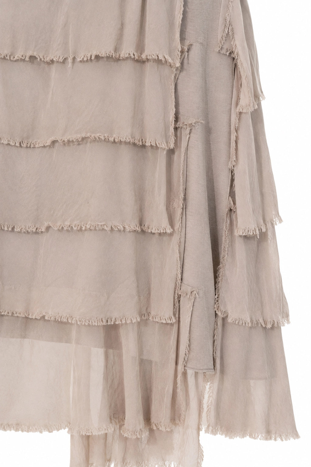 Close-up of a sheer, layered tulle garment in a light taupe-beige color, showing frayed ruffle edges against a plain white background.