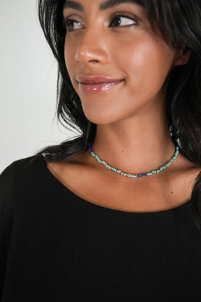 This image features an elegant necklace, primarily in shades of turquoise and cobalt. The necklace is showcased on a model who is wearing a simple, dark top, which contrasts beautifully with the vibrant colors of the beads.