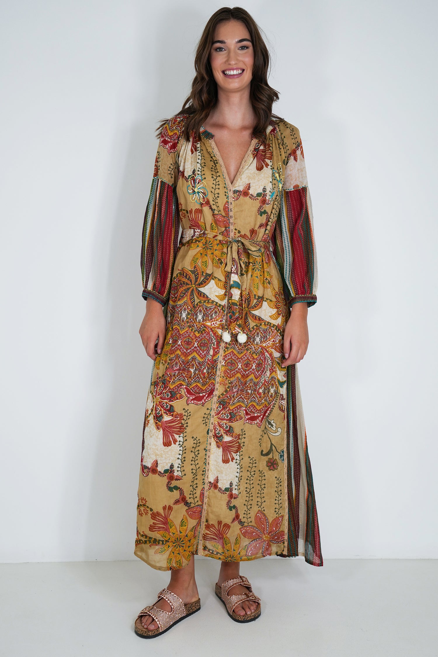 Woman wearing a patterned dress with long sleeves against a white background