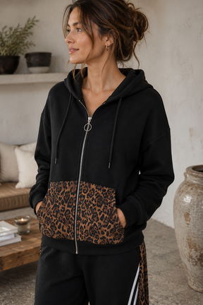 Woman wearing a black hoodie with leopard print pocket in an indoor setting