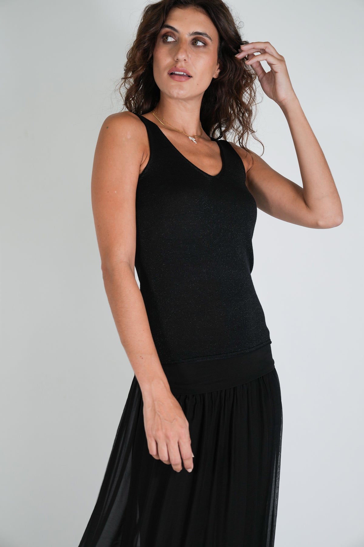 Woman wearing a black sleeveless dress against a plain background
