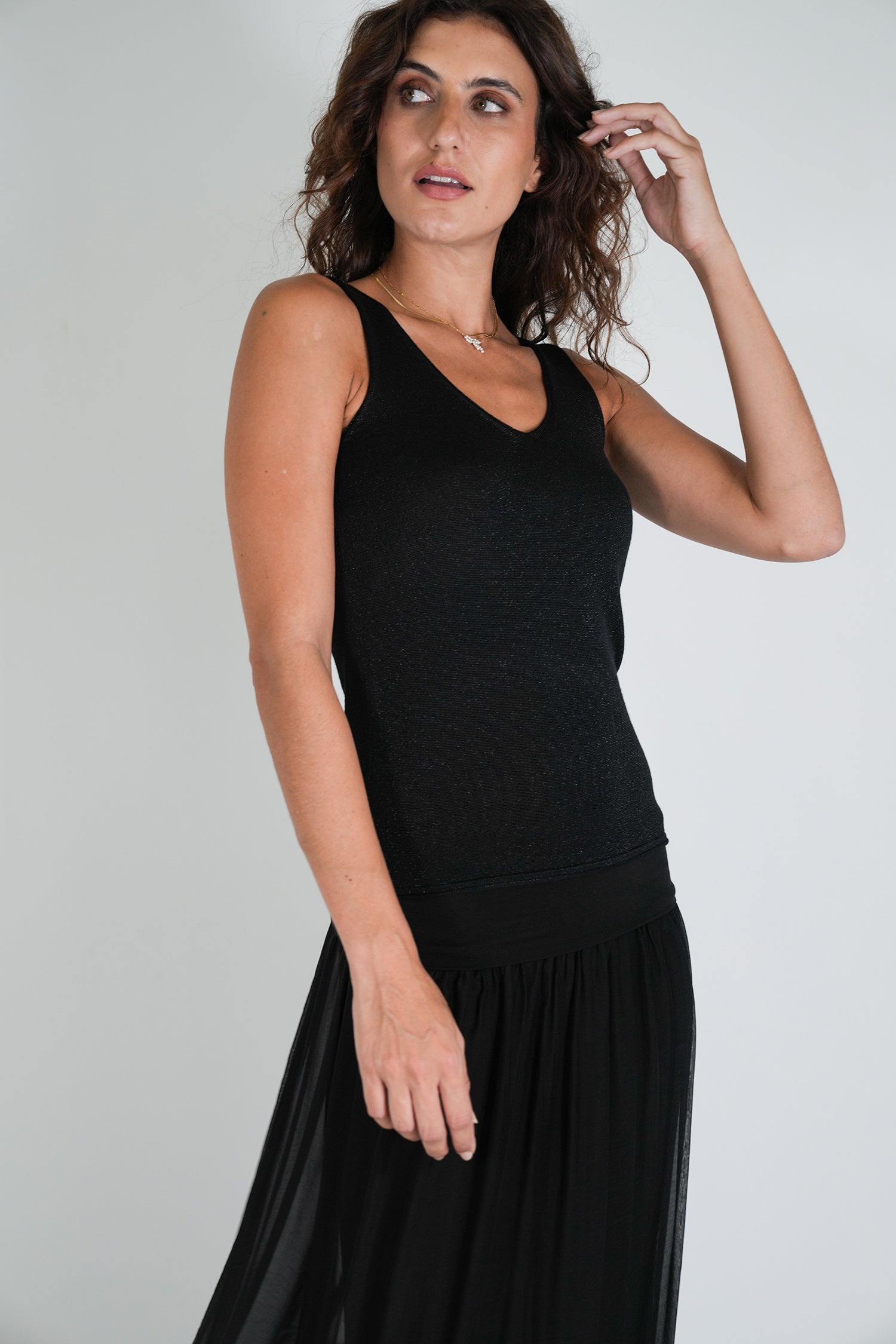 Woman wearing a black sleeveless dress against a plain background