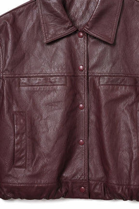 Close-up of a burgundy pleather jacket with buttons on a white background