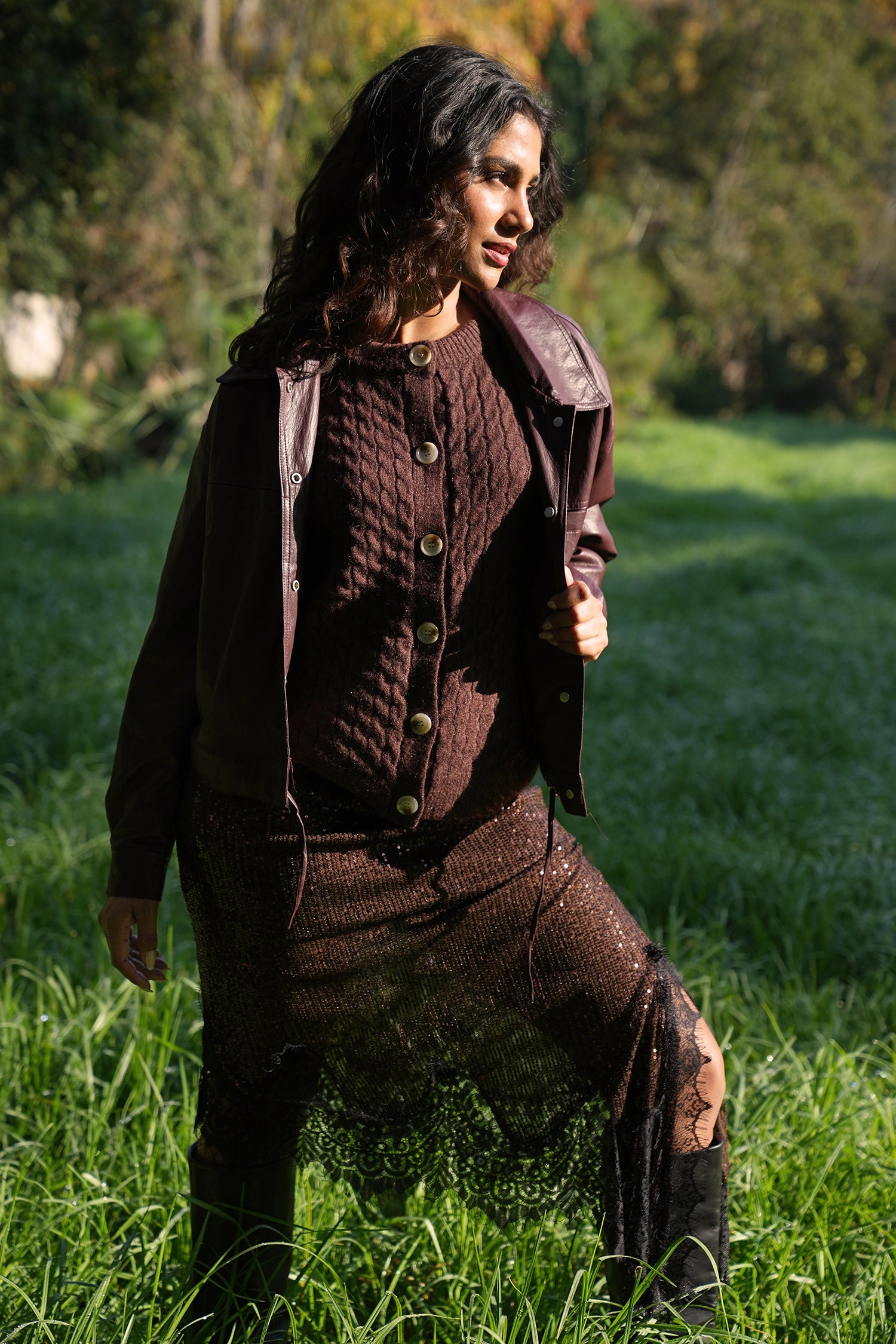 Woman in a brown outfit standing in a grassy field