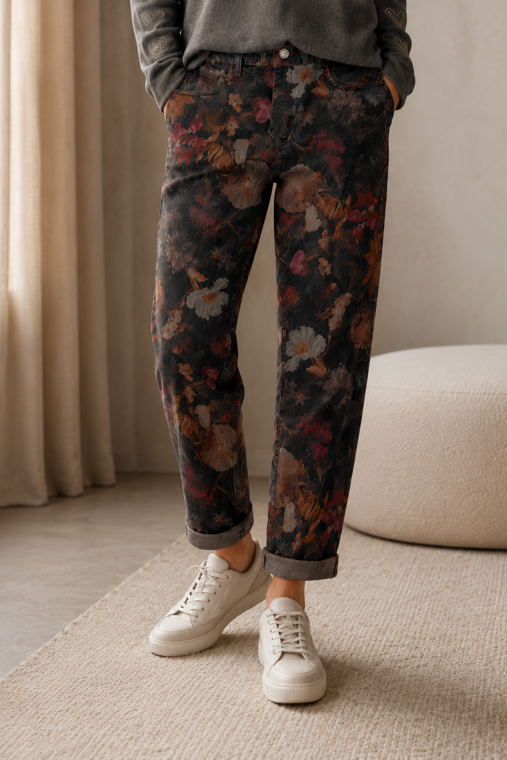 Person wearing floral pants and white sneakers indoors.