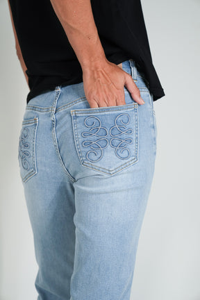 Light blue jeans with decorative stitching on a plain background