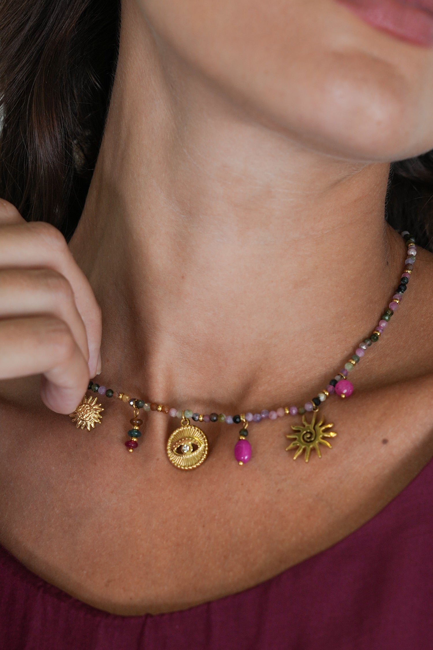 Close-up of a woman wearing a colorful beaded necklace with sun-shaped charms.