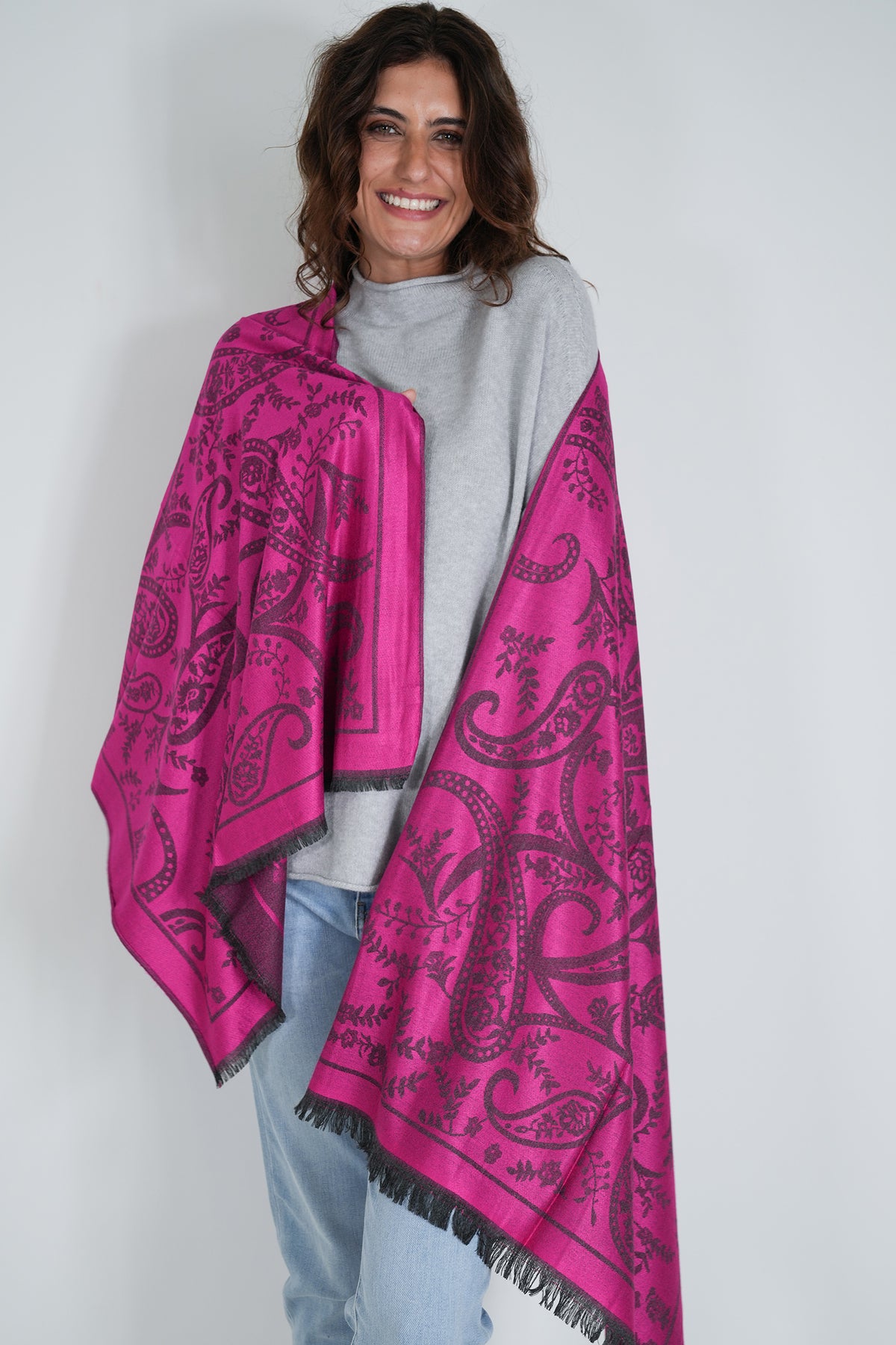 Woman wearing a bright pink patterned scarf on a white background