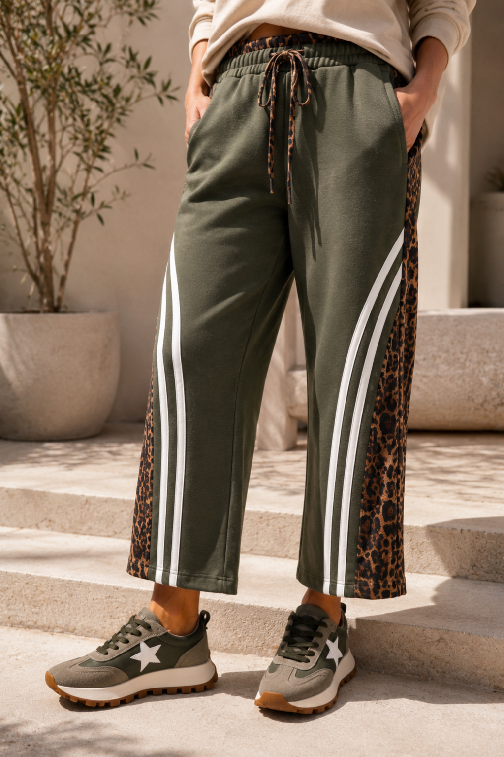 Person wearing green jogger pants with leopard print accents and white stripes, standing on steps.