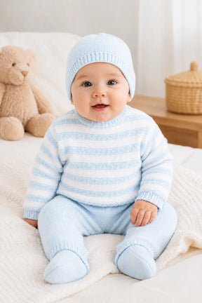 Baby wearing a blue and white striped outfit with matching hat, sitting on a white blanket.