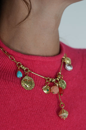 Gold charm bracelet with colorful charms on a pink sweater