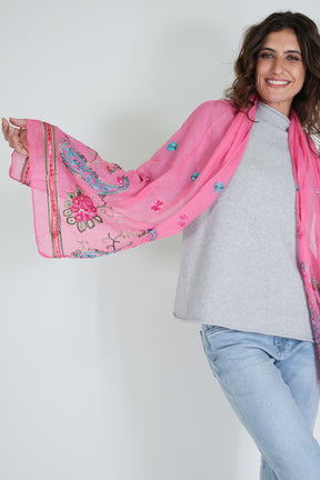 Woman wearing a pink embroidered scarf with a white background