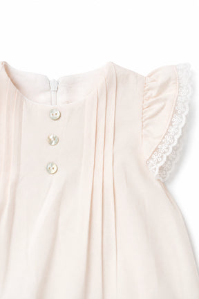 Close-up of a light pink dress with lace trim on a white background