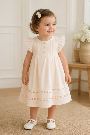 Young girl in a white dress standing indoors with a neutral background