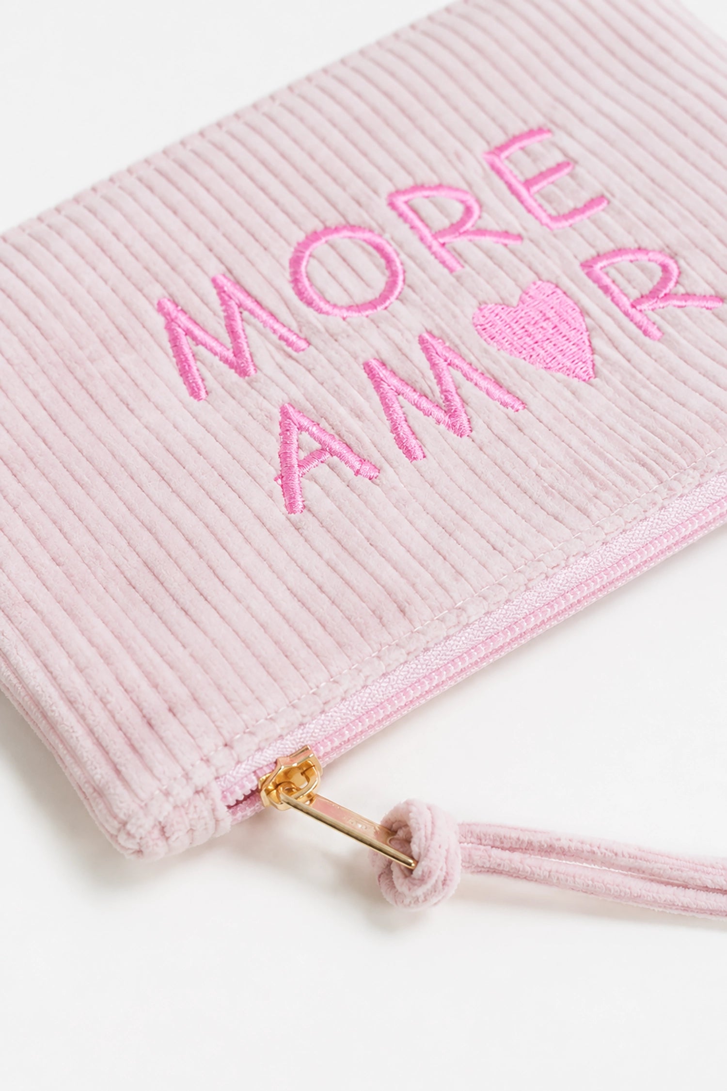 Pink textured pouch with 'More Amor' text and heart symbol on a white background