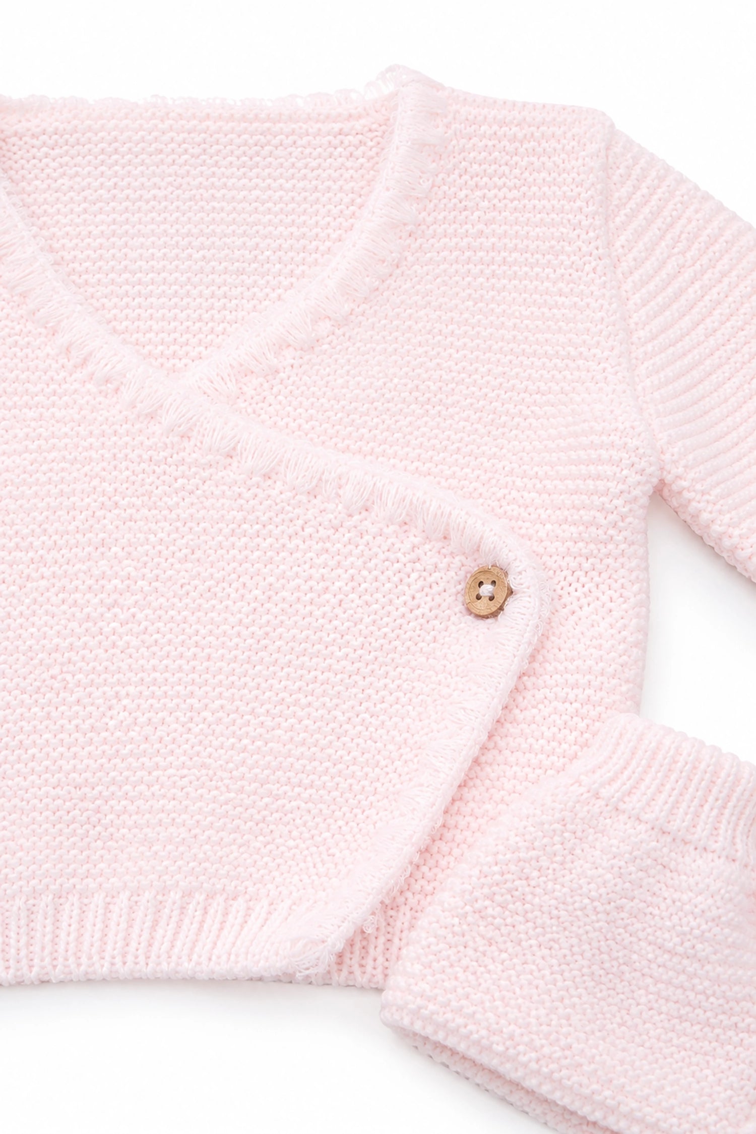 Close-up of a pink knitted sweater with a button on a white background
