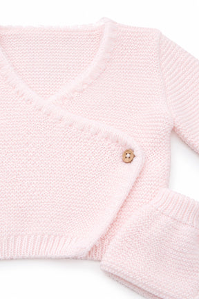 Close-up of a pink knitted sweater with a button on a white background