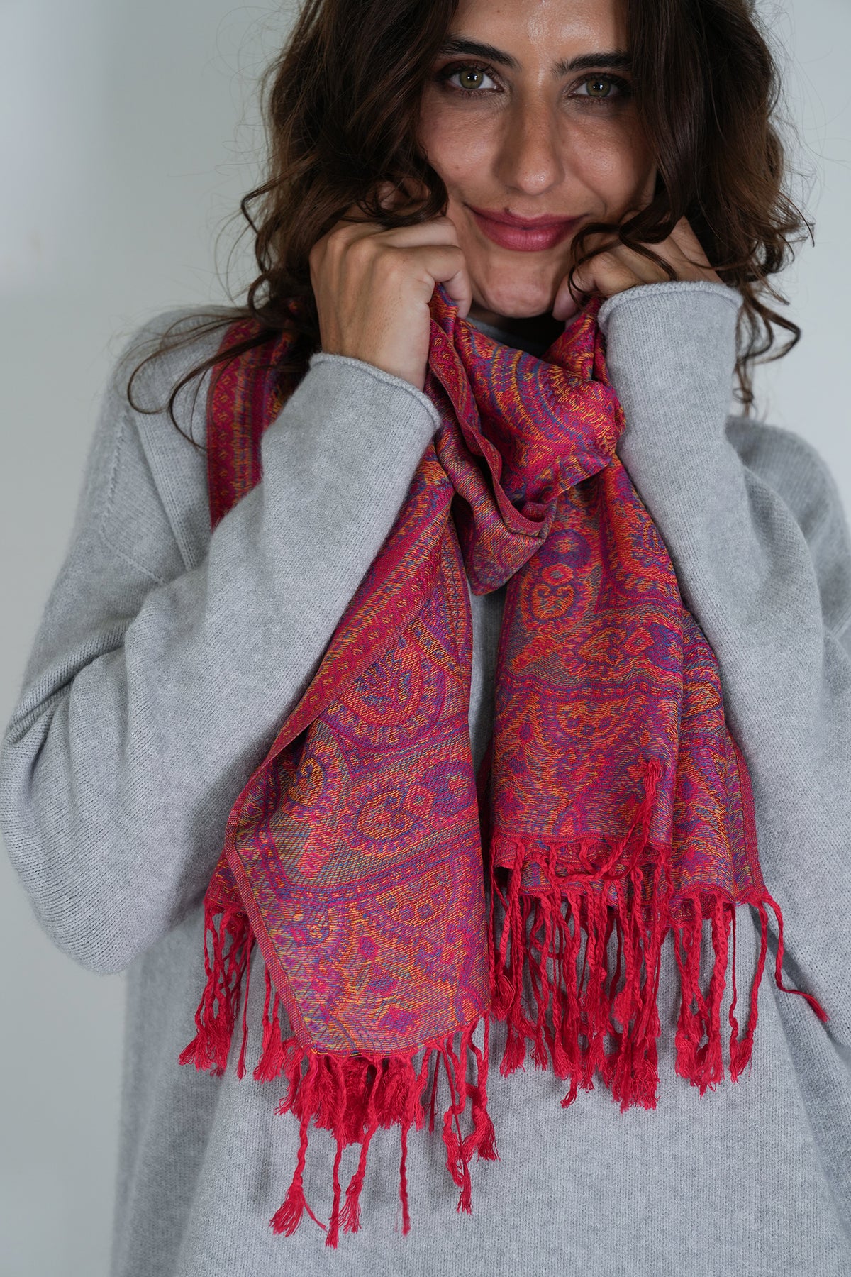 Woman wearing a red patterned scarf with a plain background