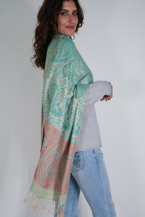 Woman wearing a teal and pink patterned scarf on a plain background